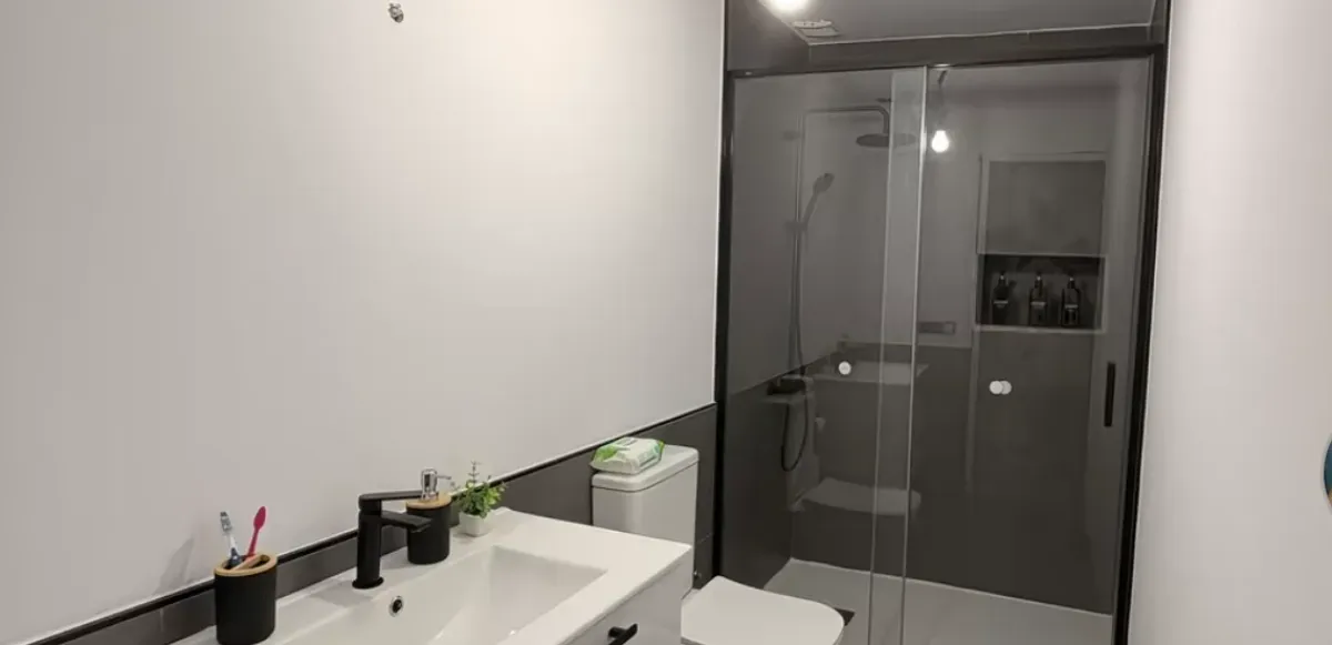 Zona de ducha con mampara y revestimiento cerámico